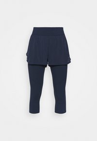 Námořnické sportovní šortky přes odpovídající tříčtvrteční legíny, které mají široký pas a perforované detaily na šortkách pro ventilaci.