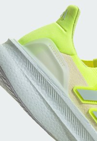 Neon dzeltas skriešanas kurpe ar teksturētu augšu, mīkstu vidusdaļu un gumijas zoli. Iekļauj formētu papēdi un atstarotājus.