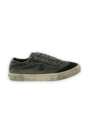 Zapatilla deportiva de lona verde oscuro desgastada, con cordones, puntera negra y suela de goma beige, vista de lado sobre fondo blanco.