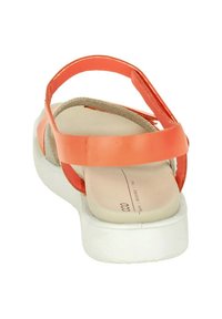 Coral patent leather sandal with a flat white sole, featuring two crossed straps on the upper and a padded beige footbed.