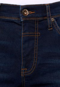 Los jeans de mezclilla azul oscuro presentan costuras naranjas, un cierre con botón de metal y un diseño tradicional de cinco bolsillos.