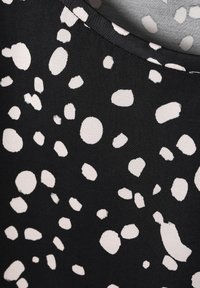 Fekete anyag fehér absztrakt pöttyökkel és szabálytalan körökkel, sima textúrával és modern mintákkal.