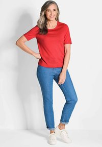 Rode trui met korte mouwen, gecombineerd met blauwe, opgerolde jeans en witte sneakers, met een ronde hals en een relaxte pasvorm.