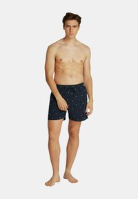 Corti da nuoto blu navy con vita regolabile, decorazioni ricamate in rosso e bianco, e una vestibilità rilassata, realizzati in tessuto leggero.