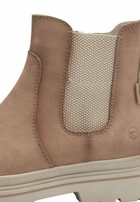 Bottine en cuir tan avec un panneau élastique beige tissé, des coutures détaillées et une semelle texturée avec des accents marron clair.