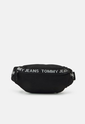 Riñonera negra con correa ajustable que presenta una tela de malla texturizada y el logo "TOMMY JEANS" en letras blancas alrededor de la banda.