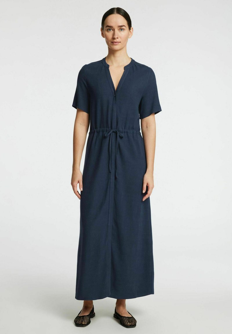 Robe maxi bleu marine à manches courtes avec un décolleté en V, taille à cordon de serrage et devant à boutons. Fabriquée en tissu léger, texture lisse.