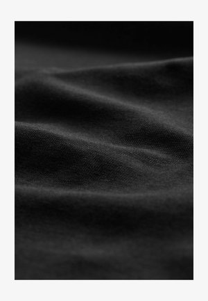 Tissu noir à la texture lisse, affichant des vagues et des plis subtils, mettant en valeur un design uni sans motifs ni marques.