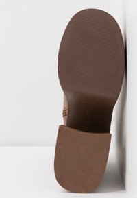 Semelle de chaussure marron avec de fines rainures horizontales, taille 37 indiquée près de la voûte plantaire, sur fond blanc.