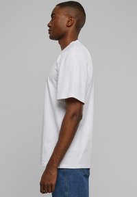 White cotton t-shirt with short sleeves, relaxed fit, round neckline, featuring smooth texture and no visible patterns or accents.