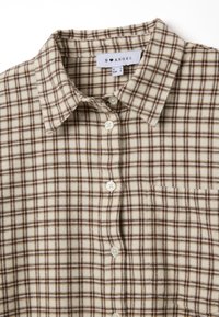 Camicia a scacchi nei toni beige e marrone, con colletto button-down, bottoni frontali e una tasca sul petto. Tessuto morbido e strutturato.