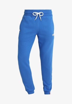 Pantaloni da jogging in pile blu con coulisse bianca, vita elastica e polsini, tasche laterali e piccolo patch con logo sulla coscia destra.