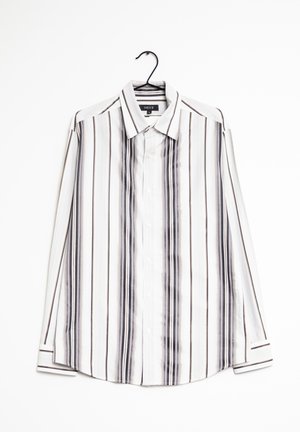 Chemise blanche à manches longues avec des rayures verticales noires et marron, suspendue sur un cintre noir sur fond blanc.