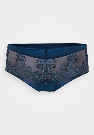 Marineblauwe kanten slip met bloemenborduring en doorschijnende overlay, met een brede tailleband en een V-vormige uitsnijding aan de voorkant.