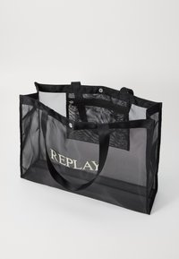 Black mesh tote bag featuring a spacious interior, dual handles, and a zippered pocket. Embroidered "REPLAY" logo on the front.