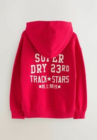 Červená mikina s kapucí, na zádech s velkým bílým grafickým textem "SUPER DRY 23RD TRACK STARS", s žebrovanými manžetami a spodním lemem.