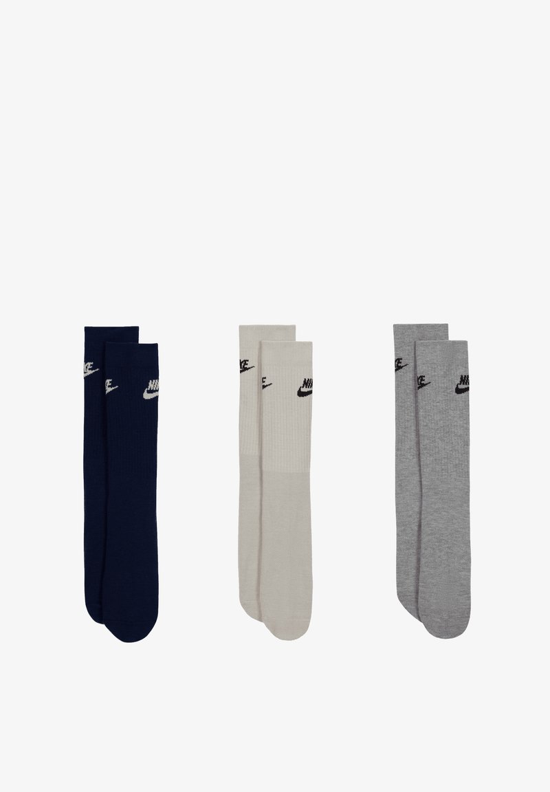 Tre par Nike-sokker: én marineblå, én beige med ribbet tekstur, og én grå. Hver av dem har Nike-logoen i svart.