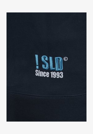 Tumesinine sviiter, millel on keskosas siniste ja valgete tikitud sõnaga "!SLD © Alates 1993". Toode on valmistatud puuvillase segu materjalist ja ribiga äärega.