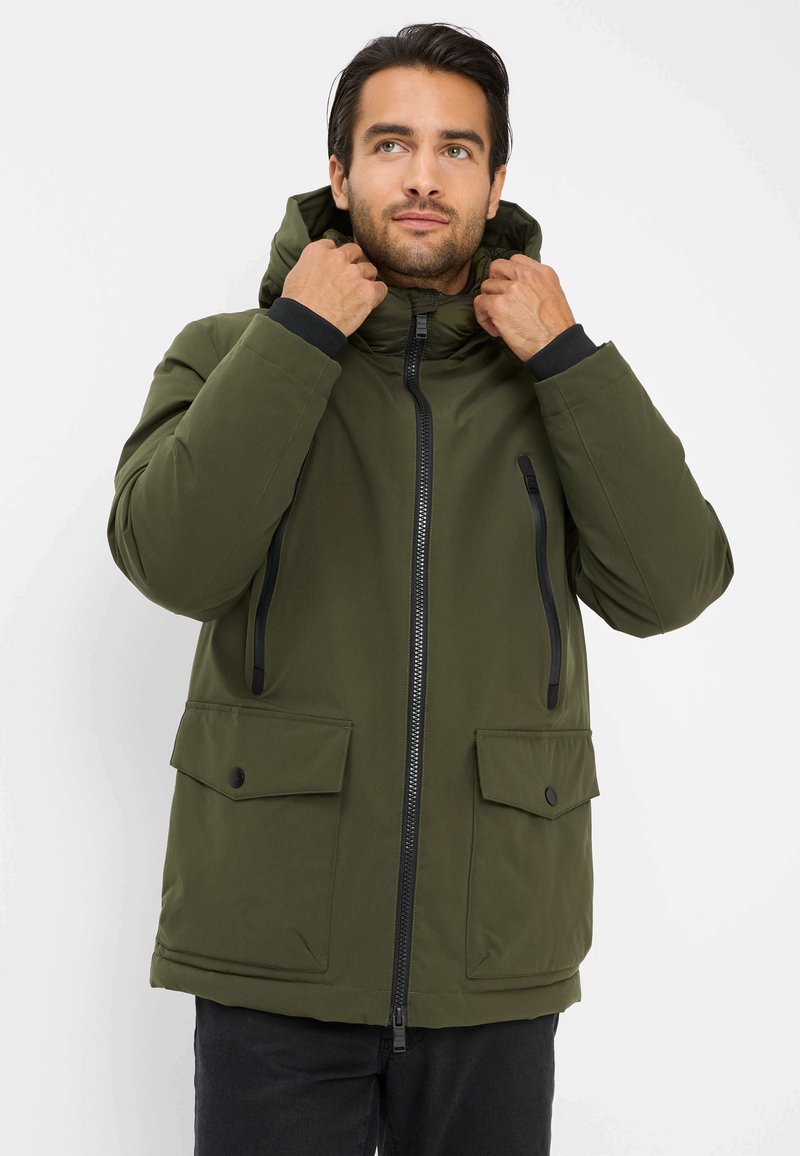 Giacca isolante verde con cappuccio, chiusura zip frontale, due ampie tasche frontali e dettagli neri sulle cerniere e sui polsini. Texture liscia.