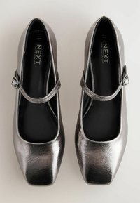 Metallisch zilveren Mary Jane-schoenen met een vierkante neus, een gestructureerde bovenkant en een slanke enkelband met een zijklink. Zwarte inlegzool zichtbaar.