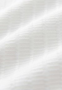 WeißerTextil mit einer subtilen gerippten Struktur, das eine weiche, gewebte Oberfläche aufweist, die unter Licht leicht reflektierend erscheint.