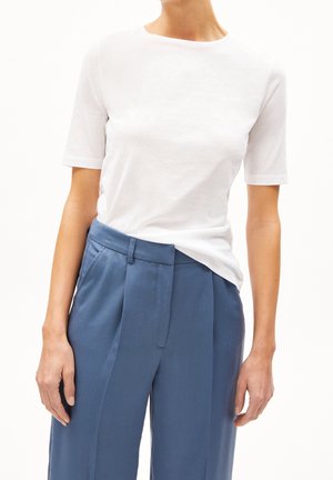 Biała bawełniana koszulka z krótkimi rękawami i okrągłym dekoltem w połączeniu z jasnoniebieskimi, dopasowanymi spodniami z przodu gładkimi i z zakładkami.