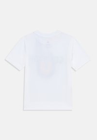 Camiseta blanca de algodón con mangas cortas, cuello redondo y un gráfico desvanecido en la parte posterior que presenta el texto "IMPRESO".