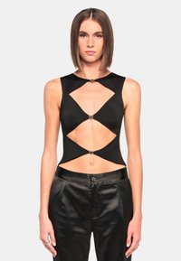 Black cutout top with a fitted design, featuring metal accents and open sections on the sides. Paired with high-waisted satin black pants.