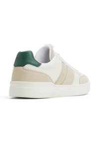Sneaker basse di colore bianco sporco con tomaia in pelle liscia e suede. Presenta un tassello sul tallone verde, accenti texture e suola in gomma.