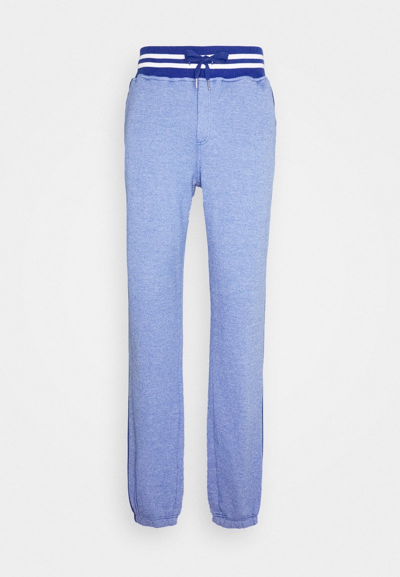 Un pantalon de survêtement bleu en matériau doux, doté d'une taille à cordon de serrage avec des rayures blanches et de poignets élastiques au niveau des chevilles.