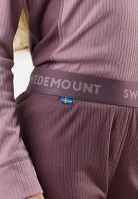 Prążkowany, teksturowany zestaw sportowy w kolorze mauve z szerokim pasem w talii z logo "SWEDEMOUNT" oraz małym niebiesko-żółtym akcentem w postaci szwedzkiej flagi.