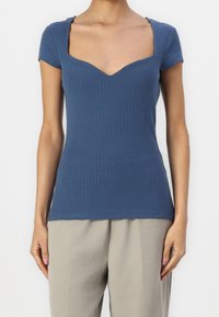 Hladký modrý top s proužky, krátkými rukávy, V-výstřihem a přiléhavým střihem. Látka má jemnou texturu a strukturovaný design.