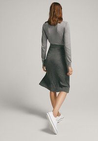 Gray ribbed knit dress with a fitted bodice and flared skirt. Paired with white sneakers, features long sleeves and a smooth texture.