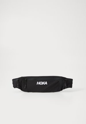Buzunar negru pentru talie, fabricat dintr-un material ușor, având două compartimente cu fermoar și un logo alb proeminent "HOKA" pe partea din față.