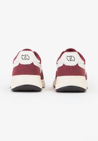 Sneakers in suede rosso e pelle bianca con suole nere, dotati di un logo sul tallone e dettagli testurizzati sui lati.