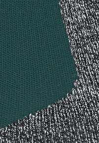 Tessuto lavorato a maglia in verde scuro e argento metallico, con un motivo testurizzato. Il design transita dolcemente tra i due colori.