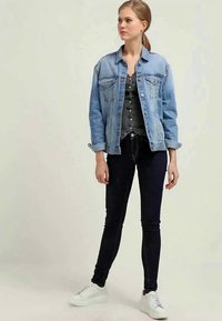 Hellblaues Denim-Jacket, dunkelblaue, enganliegende Jeans, graues, knöpfbares Oberteil, weiße Sneakers. Glatte Textur, klassisches Design mit Fronttaschen und Manschetten.