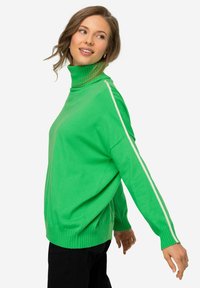 Maglione verde a maglia con collo alto, dotato di strisce laterali bianche e polsini a costine. Il materiale appare morbido e dalla texture interessante.