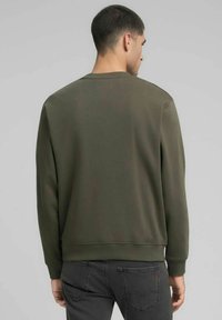 Felpa verde oliva con scollo rotondo, polsini e orlo a costine, caratterizzata da una texture liscia e una vestibilità morbida.