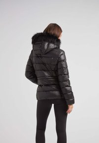 Czarna kurtka puchowa z kapturem i sztucznym futrem, z poziomym pikowanym wzorem, błyszczącą teksturą i dopasowanym krojem.