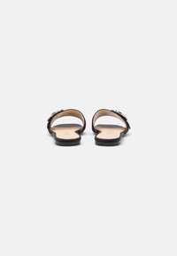 Sandali neri con suola piatta, caratterizzati da un design open-toe e decorazioni sul cinturino. Parte superiore e soletta in pelle liscia.