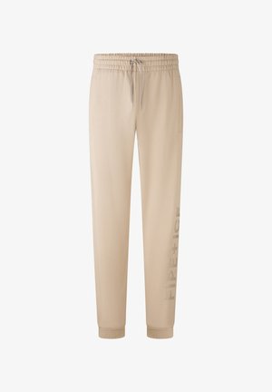 Beige sweatpants van zacht materiaal, met een elastische tailleband en drawstring, zijzakken en een gedrukt logo langs één been.