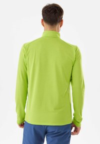 Chemise verte à manches longues en tissu texturé avec un motif en quadrillage, dotée d'un col montant et de épaules sans coutures.