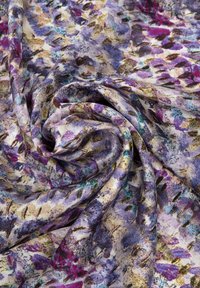 Tessuto multicolore con motivo floreale, che presenta tonalità di viola, verde e oro. Texture morbida, leggero e con un aspetto leggermente trasparente.