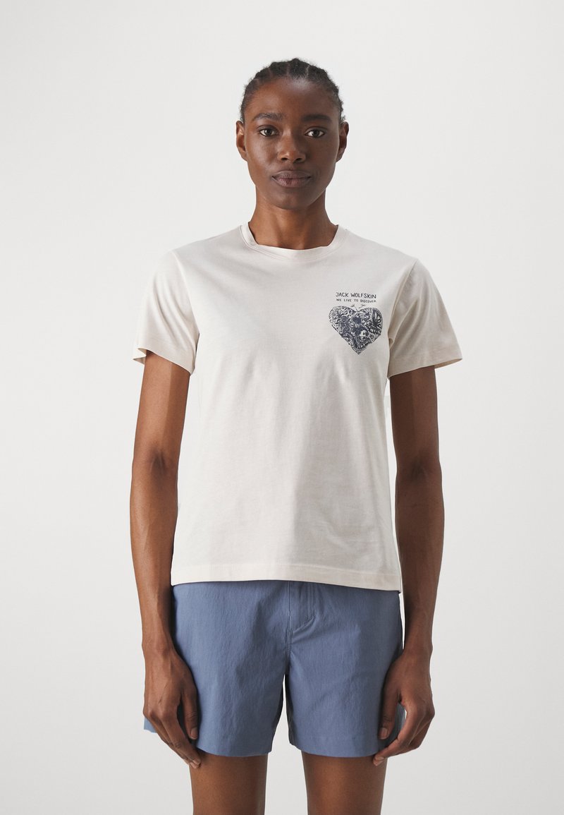Beige katoenen t-shirt met korte mouwen, voorzien van een donkerblauw hartgrafiek op de linkerborst, ronde halslijn en een relaxte pasvorm.