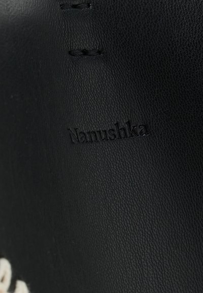 Black leather with a textured finish and visible stitching, featuring a debossed "Nanushka" logo near the bottom.