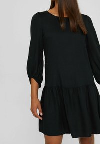 Vestido negro con mangas globo de tres cuartos y un dobladillo de volantes en capas. Tela suave con un ajuste relajado, que presenta un escote redondo.