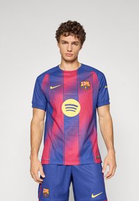 FC Barcelona fotbollströja tillverkad av andningsbart material, med vertikala blå och mörkröda ränder, Nike-logga och Spotify-grafik i gult.