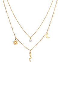 Collana a strati in tonalità oro che presenta tre catene con ciondoli a forma di sole, luna e serpente. I materiali comprendono metallo con diverse texture e finiture.