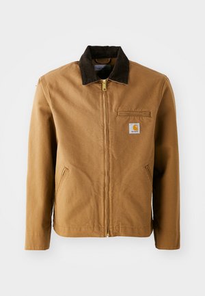 Brown canvas jacket with a dark brown corduroy collar, zip closure, chest pocket, and side pockets. Features a logo patch on the left.